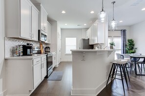 A modern kitchen with white cabinets, stainless steel appliances, and a central island with bar stools.