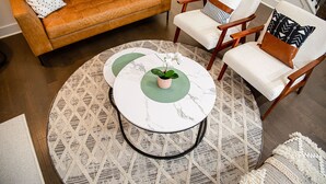 A living room with a brown leather sofa, two white armchairs, a round coffee table with a green accent, and patterned rugs. - ❤ of Stonecrest☀1556ft²☀Backyard☀Parking☀W/D (stone crest)