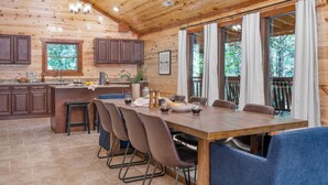 A wooden cabin with a dining area, kitchen, and large windows. - Bluestem & Bluebell by AvantStay | Incredible Views w/ Balcony & Indoor Pool! (Sevierville)