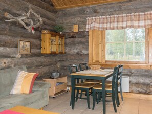 A rustic cabin interior with a wooden dining table, chairs, a sofa, a cabinet, and a window with blinds. - Lauri 2 by Interhome (Kittilä)