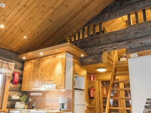 A wooden cabin interior with a kitchen area, wooden ceiling, and a loft space. - Lauri 2 by Interhome (Kittilä)