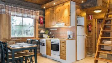 Una cucina compatta con mobili in legno, forno integrato, frigorifero e zona pranzo con tavolo e sedie.