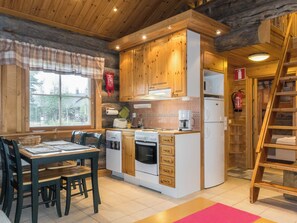 Une cuisine compacte avec des meubles en bois, un four encastré, un réfrigérateur et un coin repas comprenant une table et des chaises.