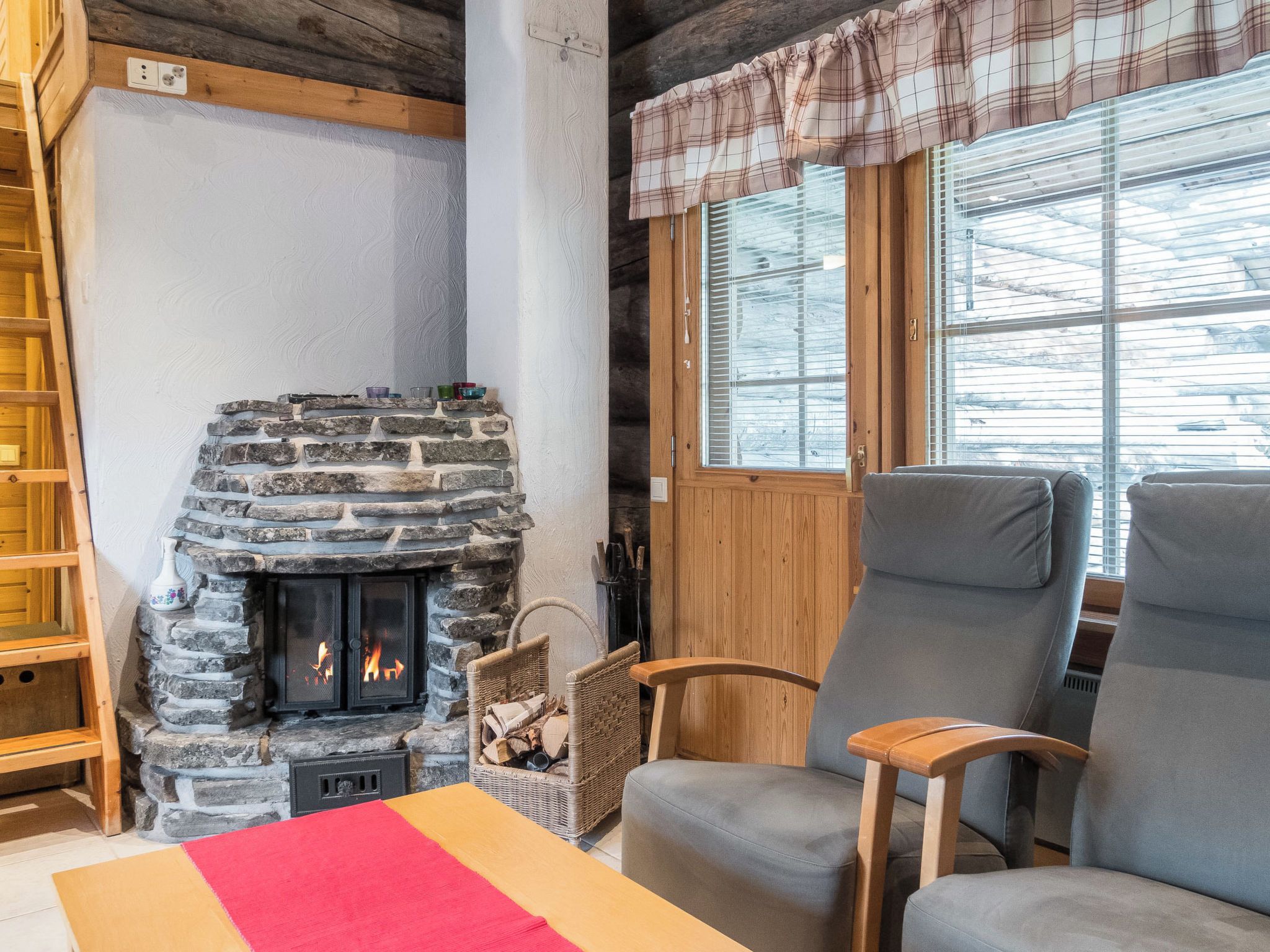Una habitación acogedora con chimenea de piedra, muebles de madera y una ventana con persianas.