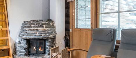 Una habitación acogedora con chimenea de piedra, muebles de madera y una ventana con persianas.