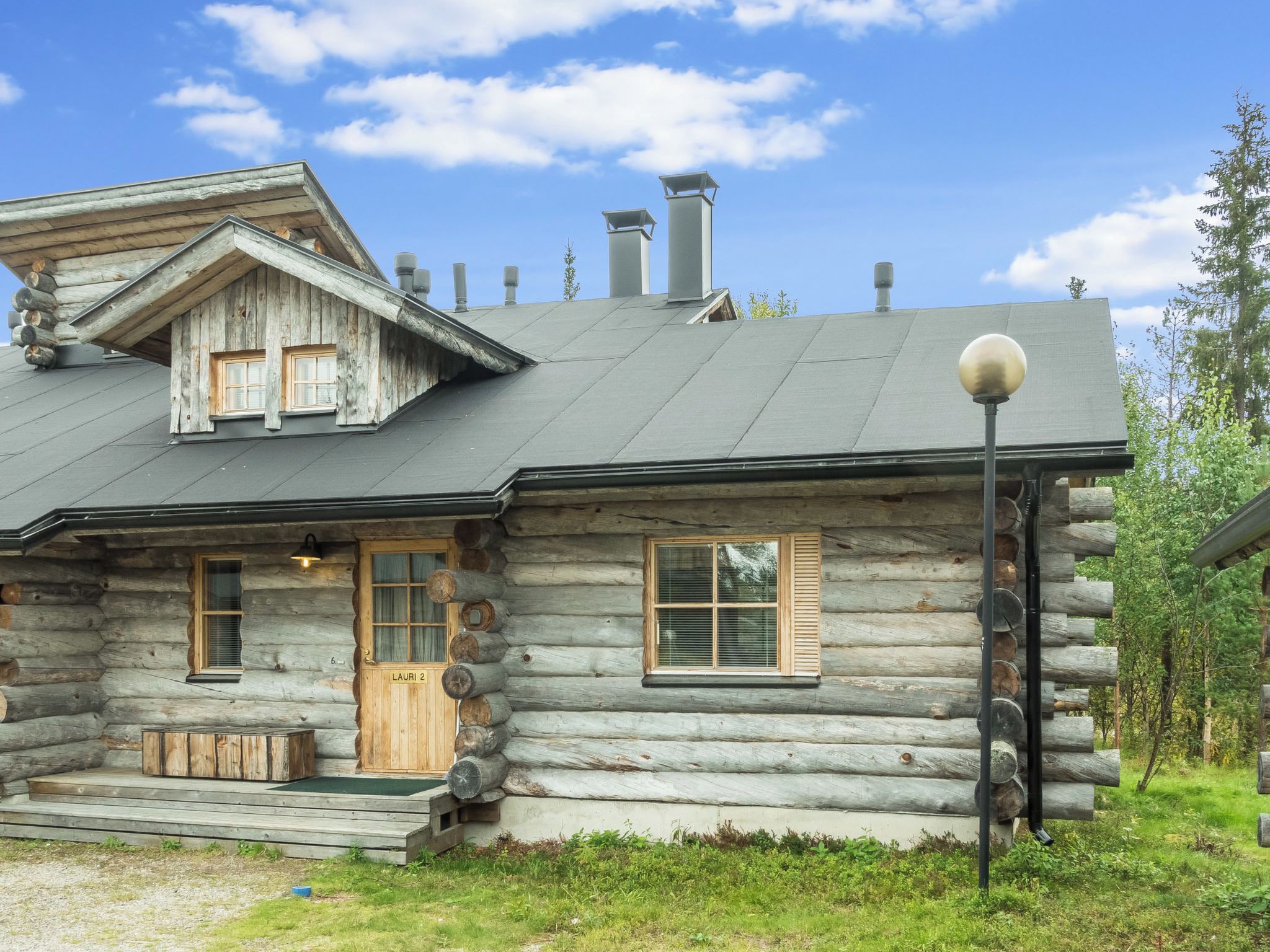 Une cabane en rondins avec un toit en pente, une véranda à l’avant et une cheminée.