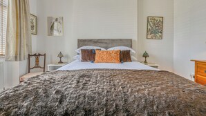 Quarto com uma cama grande, duas mesas de cabeceira e um aparador.