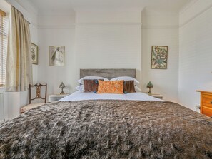 A bedroom with a large bed, two bedside tables, and a dresser.
