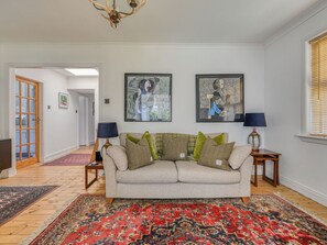 Un salon avec un canapé, deux lampes et deux œuvres d’art encadrées accrochées au mur.