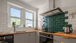 Uma cozinha compacta com máquina de lavar louça embutida, forno e janela com vista para o verde.