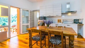 Une cuisine moderne avec des meubles blancs, une table à manger en bois et des chaises.