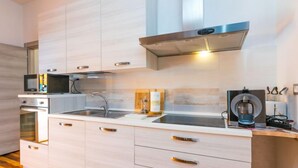 Une cuisine moderne avec des meubles en bois clair, des appareils en acier inoxydable et un four encastré.