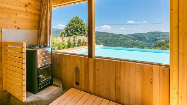 Une cabane en bois avec un plafond en bois, une fenêtre donnant sur une piscine et des montagnes, et un sauna.