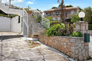 Un mur de pierre, un escalier en métal et un immeuble doté d’un balcon.