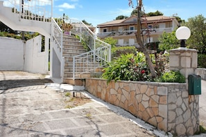 A stone wall, a metal staircase, and a building with a balcony.