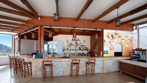 A bar area with wooden chairs, a stone counter, and a variety of bottles.