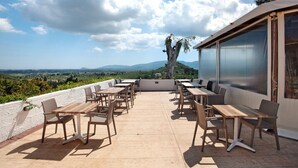 An outdoor patio with tables and chairs, overlooking a scenic landscape.