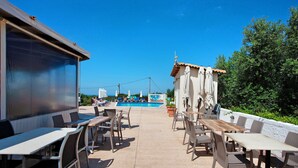 An outdoor patio area with tables and chairs, a pool, and a view of the sky.