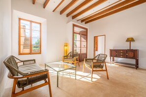 A room with a glass table, wicker chairs, a wooden cabinet, and a staircase leading to an outdoor area.