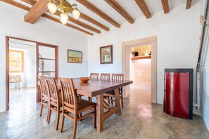 A dining area with a wooden table and chairs, a red appliance, and a staircase leading to another room.