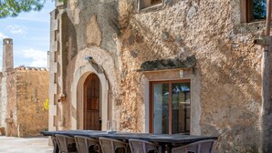 An outdoor dining area with a stone wall, a wooden door, and a table with chairs. - Country House 'Can Menut' with Mountain View, Wi-Fi and Air Conditioning (FELANITX)