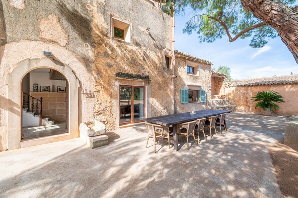 A rustic stone building with a covered outdoor seating area and a staircase leading to an upper level.