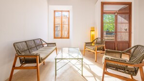 A room with a glass coffee table, wicker furniture, wooden beams, a window, and a door. - Country House 'Can Menut' with Mountain View, Wi-Fi and Air Conditioning (FELANITX)