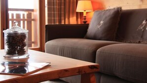 A cozy room with a wooden wall, a sofa, a table with a glass container, and a lamp. - Grand-Hôtel B35 by Interhome (Villars)