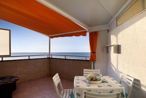 Un balcon avec une table, des chaises et une vue sur la mer.