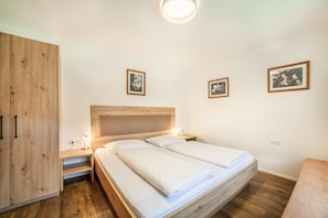 A bedroom with a wooden bed, bedside tables, a wardrobe, and framed pictures on the wall. - Holiday Apartment "Parigger Apt Lavendel" with Mountain View, Shared Garden and Wi-Fi (Racines)
