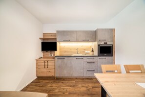 A compact kitchen with wooden cabinetry, a built-in oven, and a dining area with a table and chairs.