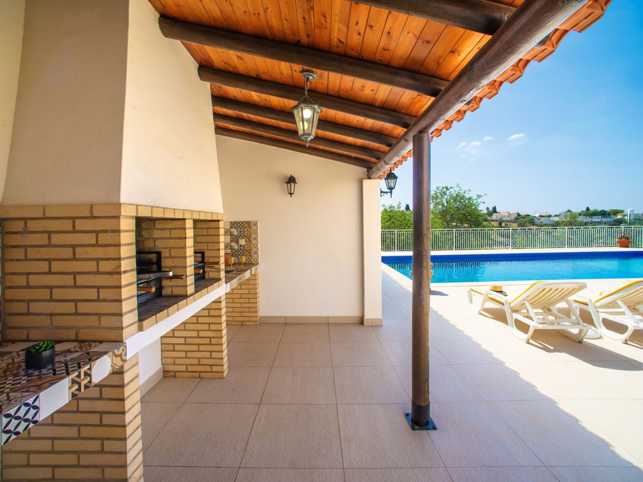 Terrassa exterior amb una barbacoa de maó, una piscina i gandules.
