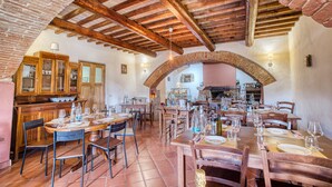 Un restaurant avec des arches en briques, des tables et des chaises en bois, et une cuisine ouverte.