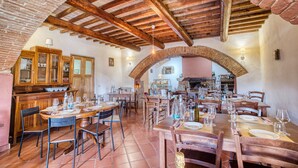 Un restaurant doté d’arches en briques, de poutres en bois et de sols carrelés. Les tables sont dressées avec des verres à vin et des assiettes.