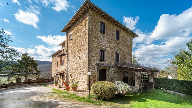 Un bâtiment en pierre doté d’un toit en pente, d’un porche abrité et d’un petit jardin.