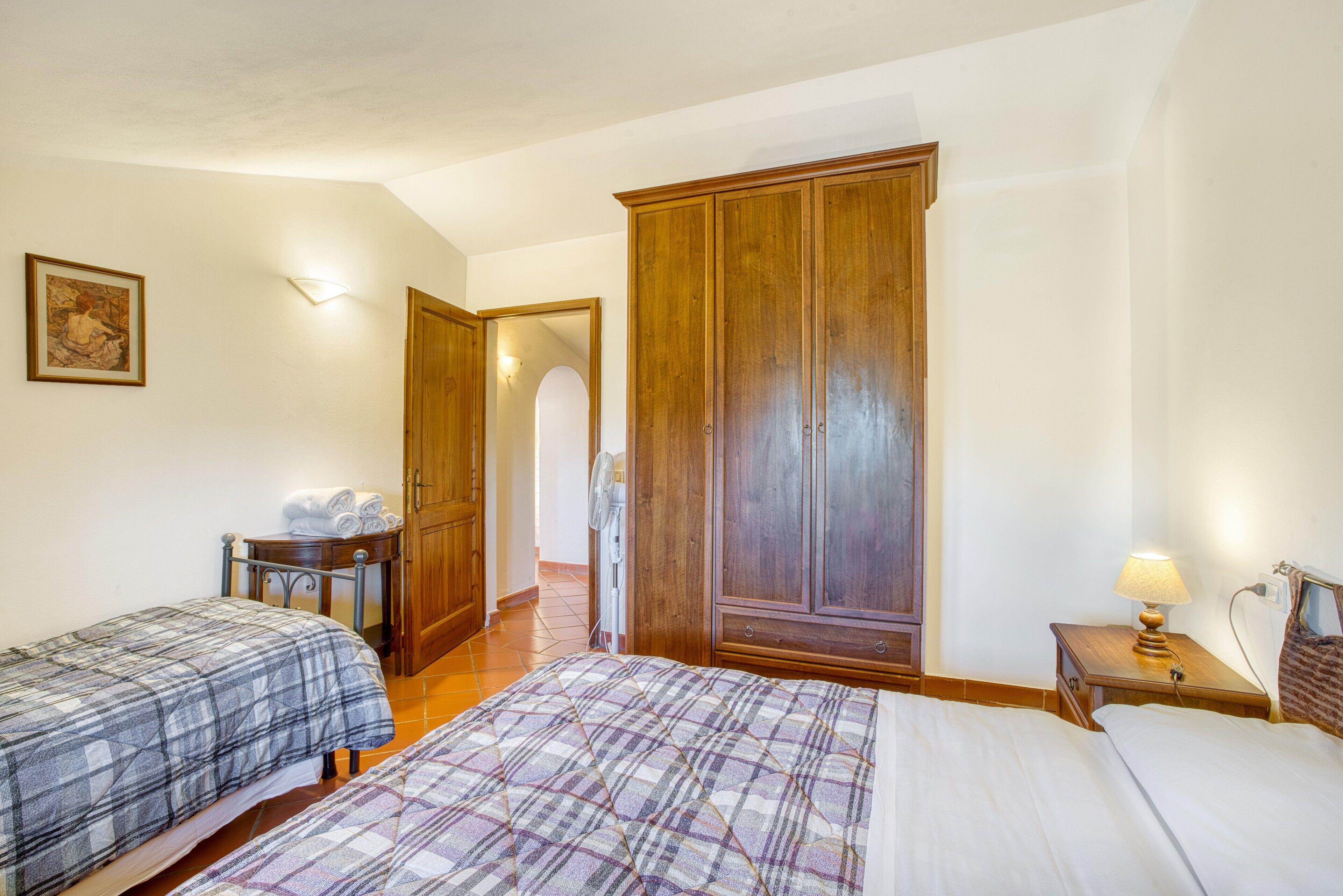 Ein Schlafzimmer mit zwei Betten, einem Holzschrank und einem Nachttisch mit Lampe.