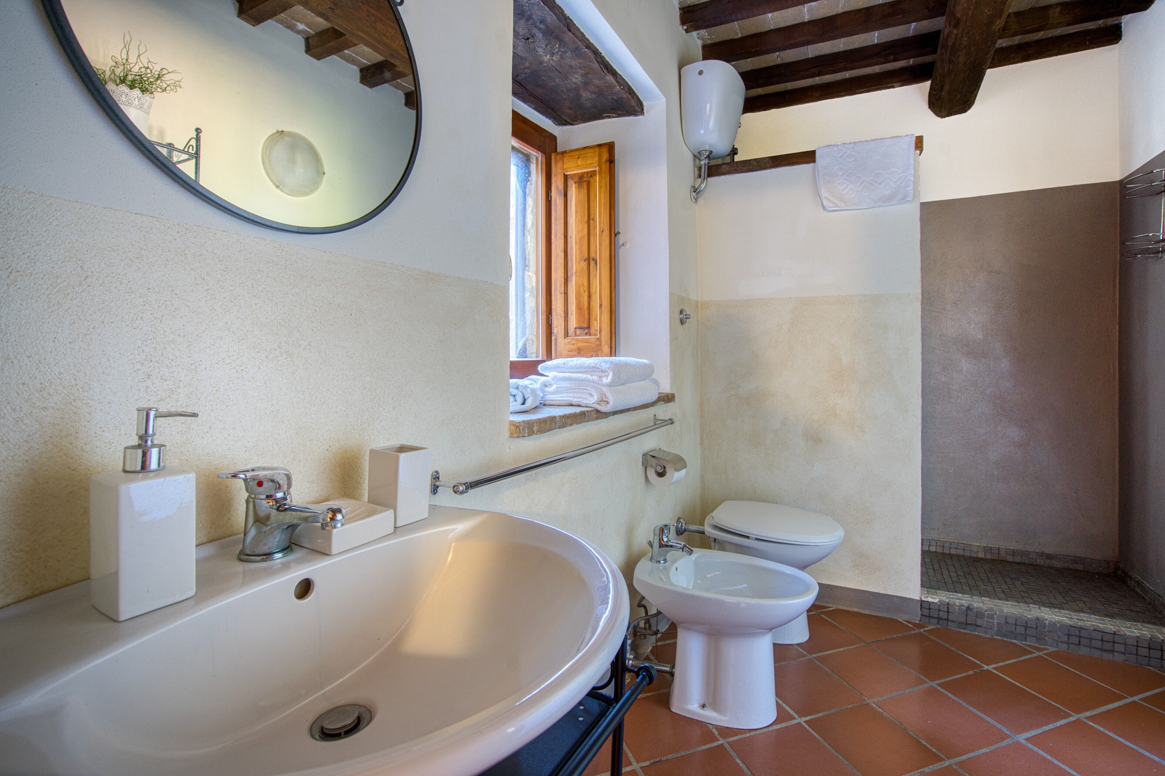 Een badkamer met een groot wastafel, toilet, bidet, spiegel en handdoekhouder.