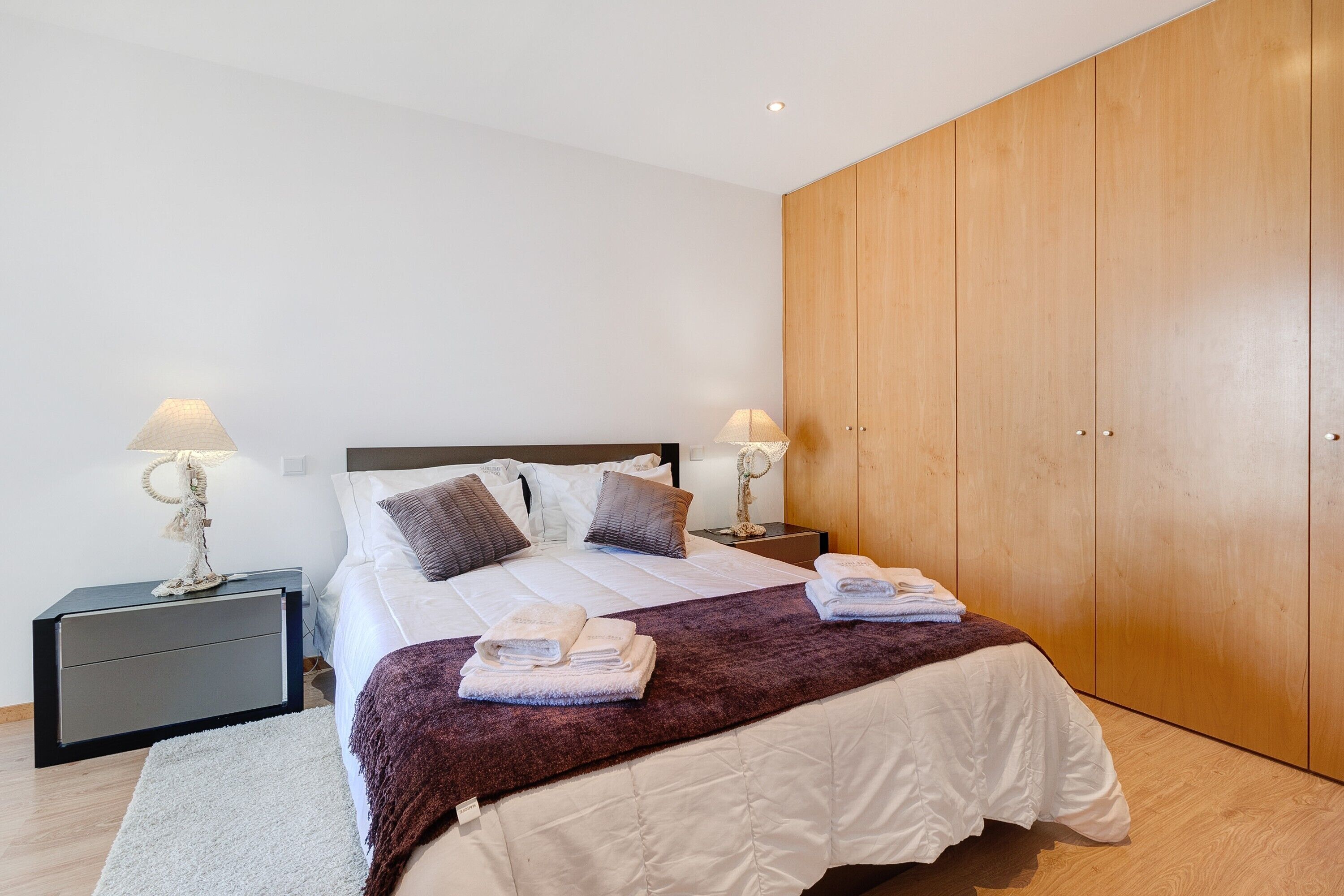 A bedroom with a bed, two bedside tables, a wardrobe, and a nightstand.