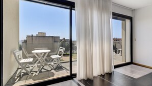 Un balcon avec une porte vitrée, des rideaux blancs et une table avec des chaises.