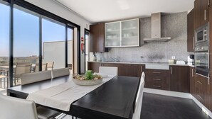 Une cuisine moderne avec des meubles en bois foncé, une hotte de cuisinière en acier inoxydable et une grande fenêtre donnant sur un paysage urbain.