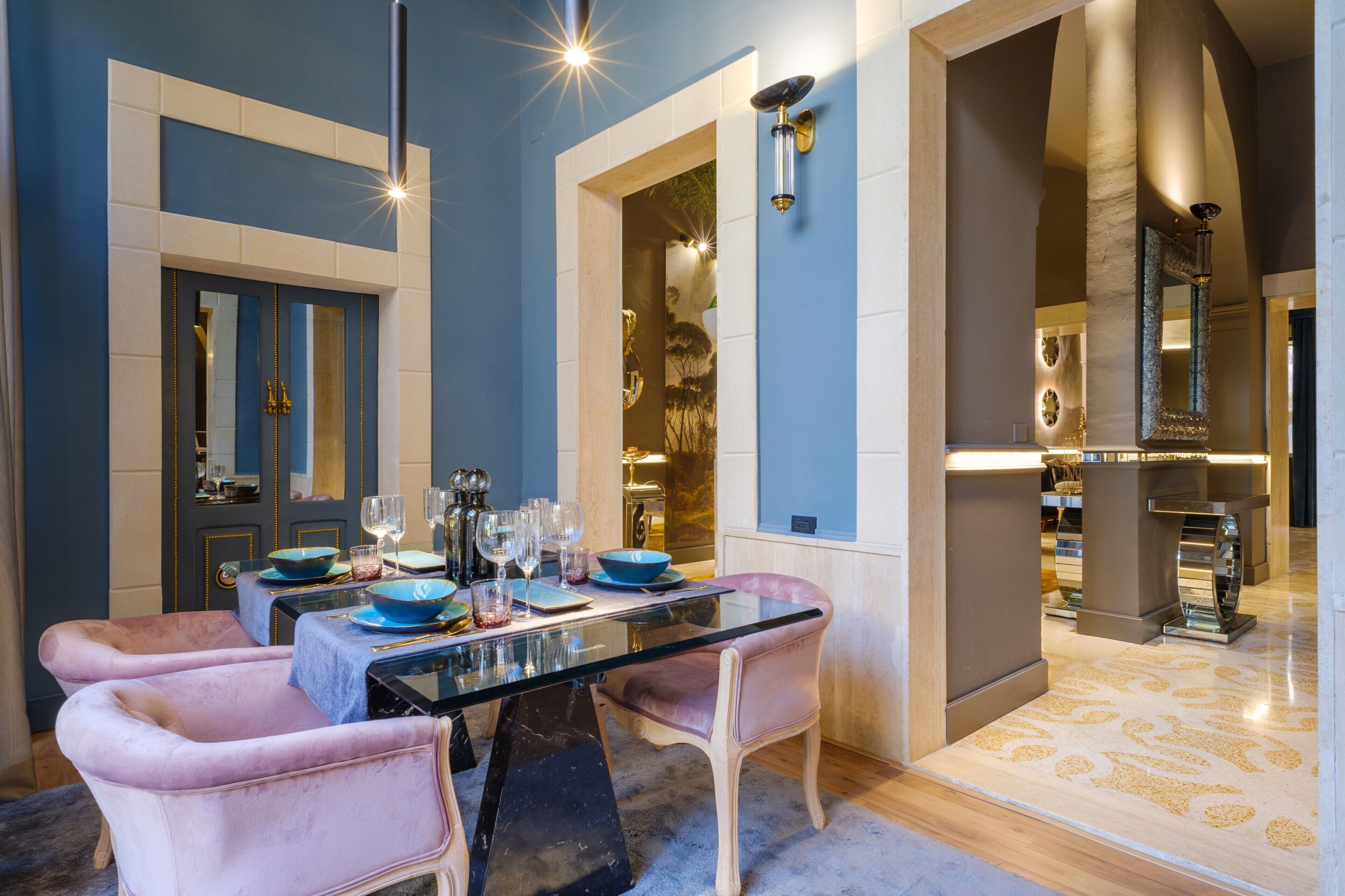 A dining area with a glass table, pink chairs, and blue tableware.