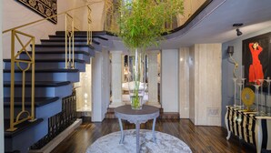 A grand staircase with a modern design, a central vase with greenery, and a decorative table with a patterned tablecloth. - Pet-Friendly Holiday Home 'Maison Boutique At Uno' with Pool & Wi-Fi (san pietro in lama)