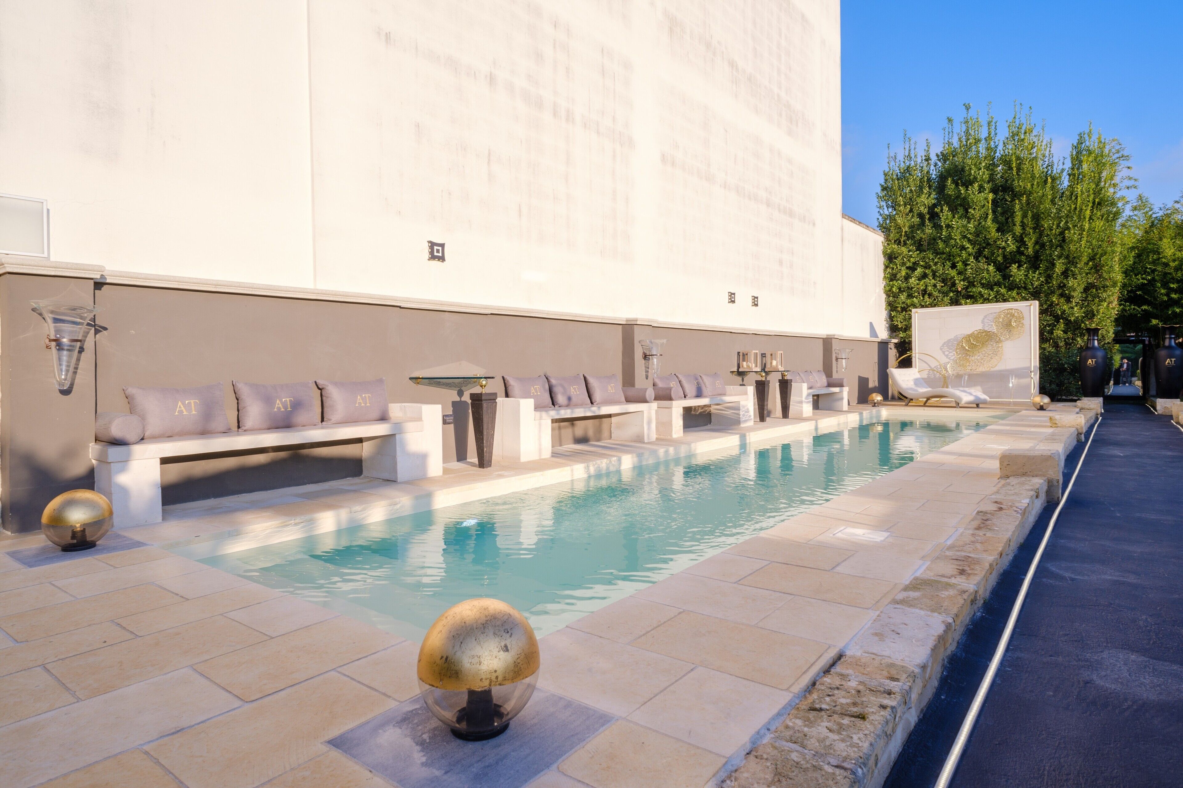A pool area with seating, a water feature, and a building facade.