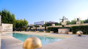 A swimming pool with lounge chairs, a decorative fountain, and a clear sky.