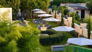 A garden with lounge chairs, umbrellas, and a pathway.