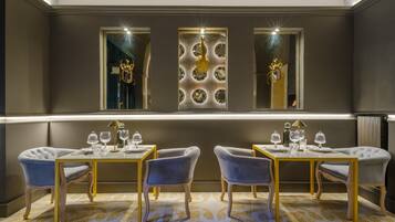 Un espace repas comprenant deux tables, quatre chaises et un mur décoratif orné de motifs circulaires.