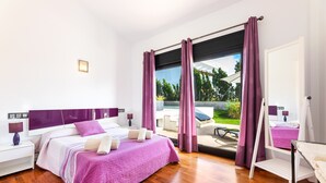 Een moderne slaapkamer met een groot bed, een nachtkastje, een bijzettafeltje, een raam met gordijnen en uitzicht op de omgeving.
