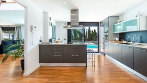 Een moderne keuken met een centraal eiland, donkere kastjes en uitzicht op een zwembad.