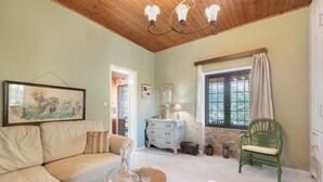 A living room with a sofa, a coffee table, a green chair, a dresser, and a window with curtains. - Stone house among trees with private garden, terrace & Wi-Fi (?ea? ??d???a?)