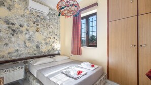 A bedroom with a stone wall, a bed with white linens, a wooden wardrobe, and a window with a view. - Stone house among trees with private garden, terrace & Wi-Fi (?ea? ??d???a?)